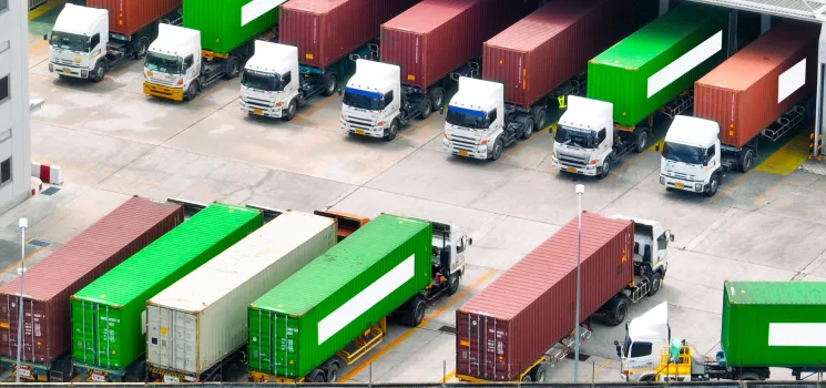 Image of cargo trucks lined up and supplying a power plant. 